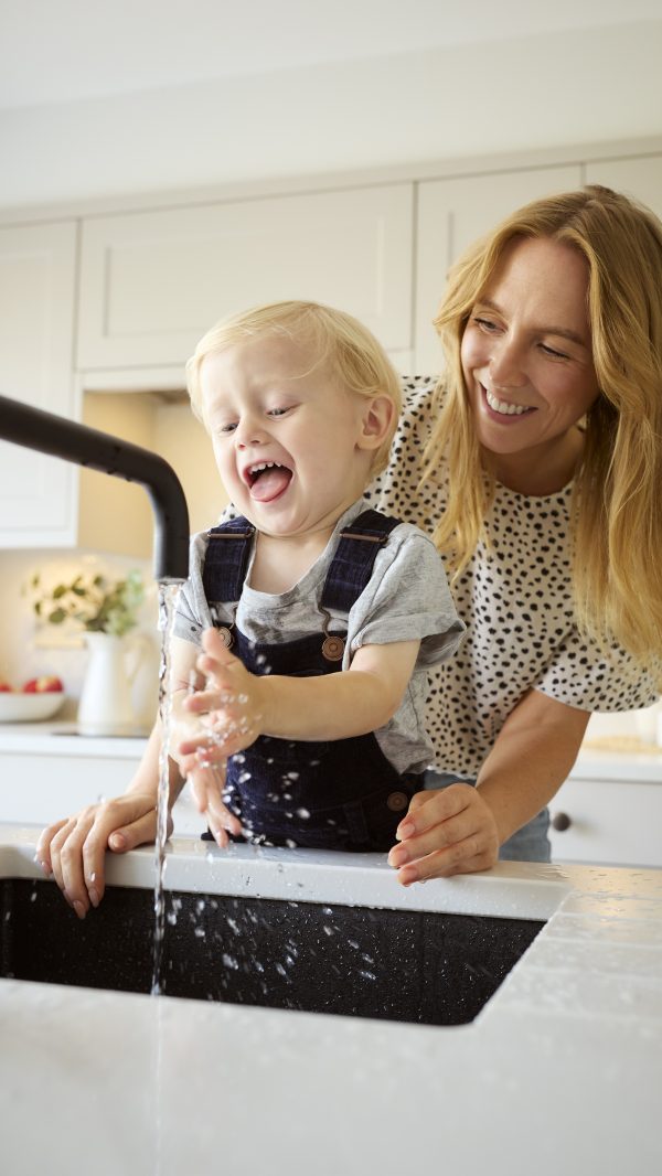 Mother With Son At Home In Kitchen Washing Hands In Sink Or Basin Together softening water